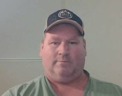 Blake Cowan, in a ball cap, photographed at his desk